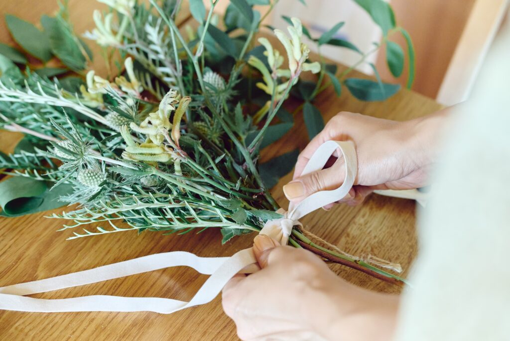 005-1024x684 a woman ties a ribbon on her flower arrangement